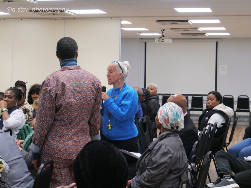 An audience member speaking into a microphone during a public conversation